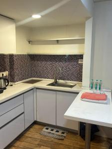 a kitchen with white cabinets and a sink at Rajhans Belizia JSM in Surat