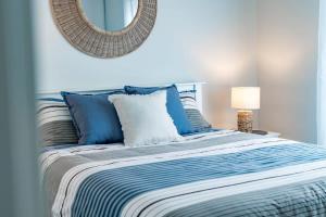 een bed met blauwe en witte kussens en een spiegel bij 11 Southern Right Crs Encounter Bay - No Linen Included in Encounter Bay