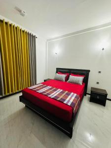 a bedroom with a red bed and yellow curtains at The Kandyan Secret Villa - Free Pick up From Kandy Railway Station in Kandy