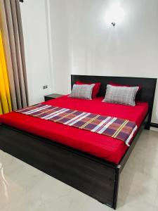 a large bed with a red blanket and pillows on it at The Kandyan Secret Villa - Free Pick up From Kandy Railway Station in Kandy