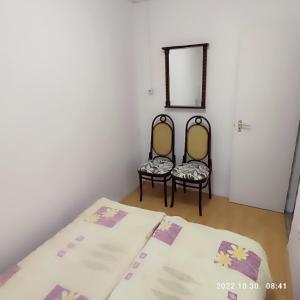 a room with two beds and two chairs in it at LBB apartman in Sátoraljaújhely