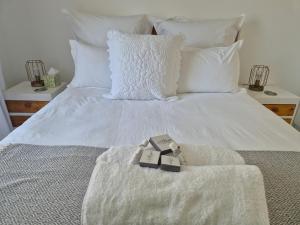 uma cama branca com almofadas brancas e dois bilhetes em A&F Cottage with pool n braai em Sandton