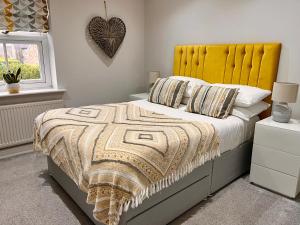 a bedroom with a bed with a yellow headboard at Castle Cottage in Harrogate