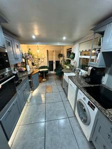 a kitchen with white cabinets and a washer and dryer at My Sky LDN Secret Garden in London