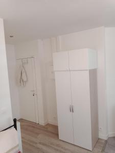 um quarto branco com um frigorífico branco e uma porta em Joli em Clichy