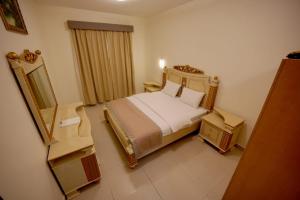 AL MARJAN FURNISHED APARTMENTS في عجمان: غرفة الفندق بسرير ومرآة