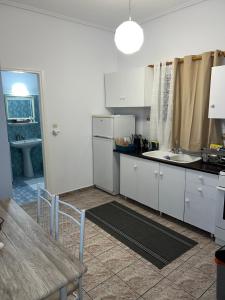 una cucina con armadi bianchi, tavolo e lavandino di Alexandra’s apartment a Paralía Akrátas