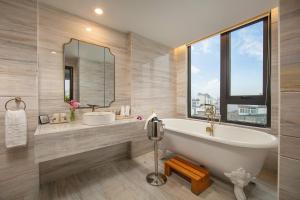 a bathroom with a tub and a sink and a mirror at The Oriental Jade Hotel in Hanoi