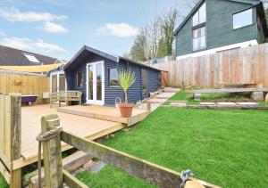 a backyard with a blue house and a wooden deck at Dart View Cabin in Totnes