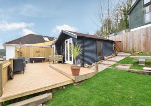 un patio trasero con una terraza de madera y una casa en Dart View Cabin en Totnes