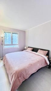 1 dormitorio con 1 cama grande con sábanas rosas en Logement avec parking à 11 min de Paris et 15 min de la défense Arena, en Argenteuil