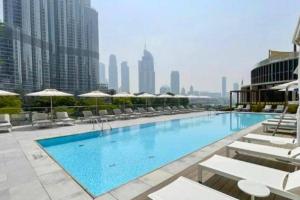 a large swimming pool with chairs and umbrellas on a building at 2Bed Dubai Address Opera Residence sea view - Downtown near Burj Khalifa- 5 min walk Dubai mall in Dubai