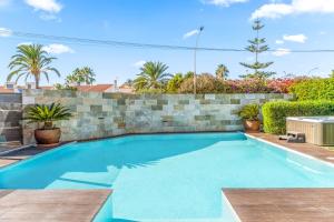a swimming pool in a backyard with a stone wall at Villa Paradise in El Campello