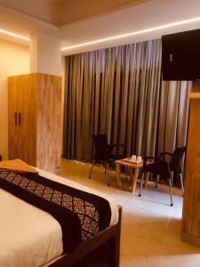 una camera d'albergo con letto, tavolo e sedie di RAINBOW ROOMS a Kozhikode