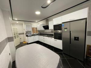 a kitchen with white cabinets and a black refrigerator at Grande maison moderne à Ajdir Al Hoceima 12 voyageurs Confort & espace garantis in Al Hoceïma