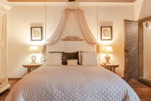 a bedroom with a large white bed with two lamps at LA FINESTRA SUL TRAMONTO Dimora Storica in Laterina