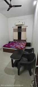 a bedroom with a bed and two black chairs at Shri mallick Mangalam in Korba