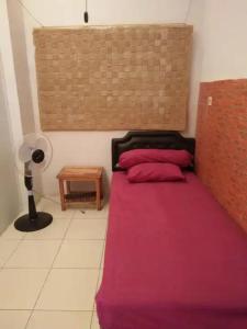 Rumah Kost 10 Gambir في جاكرتا: غرفة نوم مع سرير وملاءات وردية وطاولة