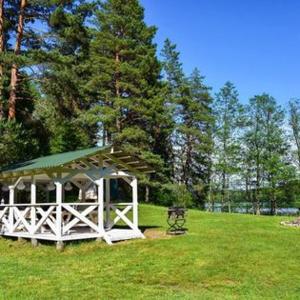 a gazebo with a bench in a field with trees at Miško Maudynės in Kaltanėnai