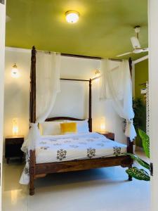 a bedroom with a canopy bed with white curtains at SEPIA STOREYS in Porvorim