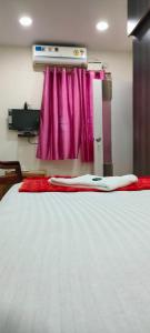 a bedroom with a white bed with pink curtains at ANDAMAN EXQUISITE in Port Blair