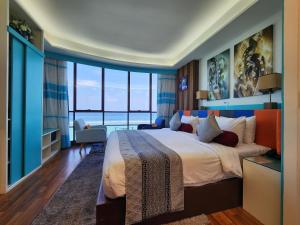 a bedroom with a large bed and large windows at The Hive Beach in Male City