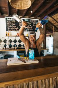 Uma mulher está a fazer uma bebida no balcão. em Jungalow em Gili Trawangan