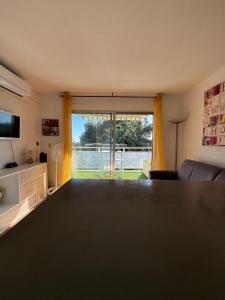 een woonkamer met een tafel en een groot raam bij Beau studio climatisé face à la mer in La Ciotat