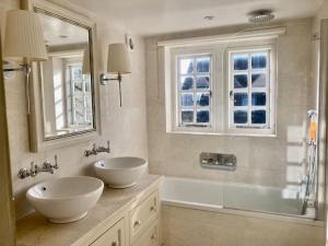 a bathroom with two sinks and a shower and a mirror at Fabulous Grade 2 Listed Home in Heart of Stow in Stow on the Wold