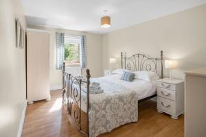 a white bedroom with a bed and a window at Harvest Cottage and Holly Barn in Yarm