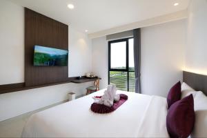 a bedroom with a white bed with purple pillows at ValStar Hotel Canggu in Canggu