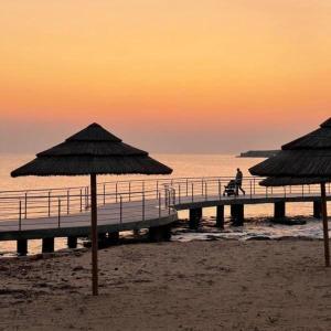 a pier with umbrellas on the beach at sunset at Freij Beach Hotel Adults Only in Ayia Napa