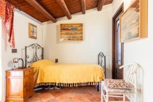 1 dormitorio con 1 cama amarilla y 1 silla en casa Ennio, en Ciminna