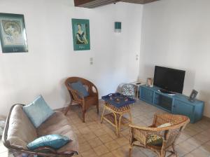 ein Wohnzimmer mit einem Sofa und einem TV in der Unterkunft Enchanté ! Chambres d'hôtes Brocéliande in Mauron
