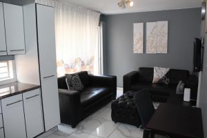 a living room with a black leather couch and a table at Beyond Comfort Apartment in Pretoria