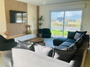 sala de estar con sofá, sillas y ventana en Au pied des batteries, en Longues-sur-Mer