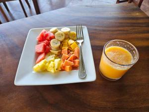 un plato de fruta en una mesa con un vaso de zumo de naranja en Oyado Marufuku en Kandy