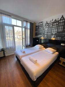 a bedroom with two beds and a large window at Hotel Old Quarter in Amsterdam