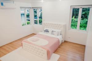 a white bedroom with a bed and two windows at พูลวิลล่ากรุงเทพ ลาดพร้าว in Bangkok