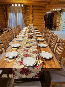 een lange houten tafel met borden en glazen erop bij Pensiunea Casa Cătanelor in Leordina