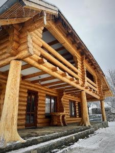 una baita di tronchi con tetto in legno nella neve di Pensiunea Casa Cătanelor a Leordina