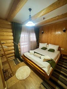 een slaapkamer met een groot bed in een kamer met houten wanden bij Pensiunea Casa Cătanelor in Leordina