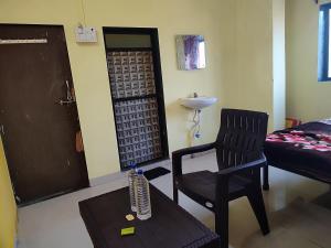 Sala de estar con silla negra y mesa en Shri Krupa Homestay, en Diveagar