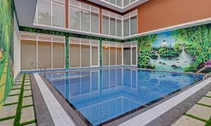 科钦Treebo Golden Terminal, Kochi Airport的一座建筑的一侧,设有一座带壁画的游泳池
