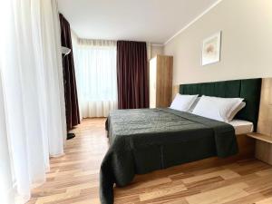 a bedroom with a bed with a green headboard at Sineva Del Sol Apartments in Sveti Vlas