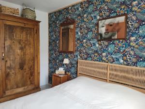 ein Schlafzimmer mit einem Bett und einer Tapetenwand in der Unterkunft Années 80, enquête et jeux hors du temps in Saint-Romain-le-Preux