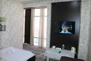 a room with a television on a wall with a table at Diamond Hotel Dushanbe in Dushanbe