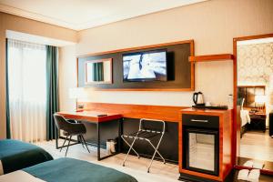 a hotel room with a desk and a tv on the wall at Grand Vaves Hotel in Trabzon