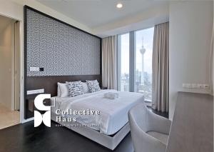 een slaapkamer met een bed, een stoel en een raam bij Tropicana Residences Kuala Lumpur by Collective Haus in Kuala Lumpur