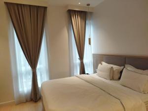 a bedroom with a large white bed with windows at AP Concept Hotel in Petaling Jaya